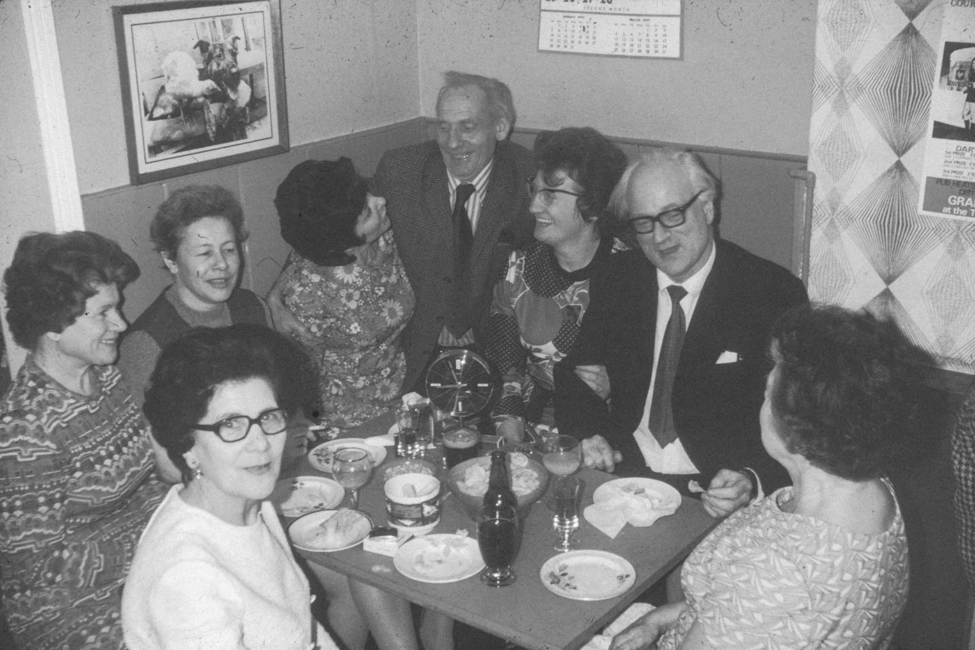 Foto antigua en blanco y negro de una familia celebrando alrededor de una mesa